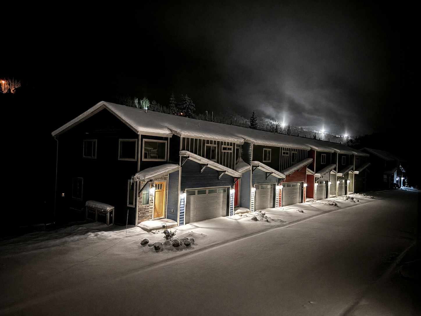 Snow-covered Brian Head vacation homes beneath the illuminated ski slopes at night